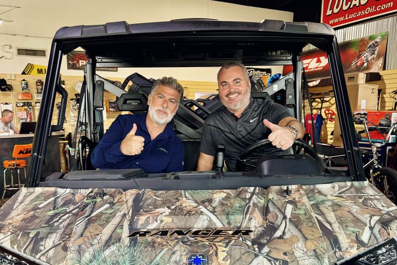 Mark Mason Jr. giving a thumbs-up from the driver’s seat of a camouflage Polaris Ranger in a powersports showroom