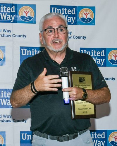 Mark Mason Sr. speaking at the United Way of Kershaw County awards, holding the Jake F. Watson Award plaque