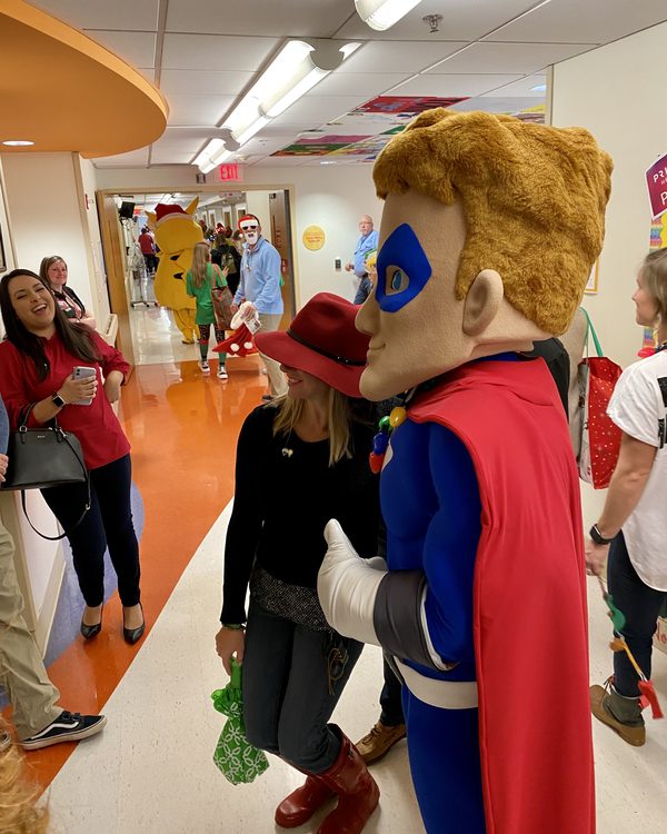 Mighty Max walks a hallway at the Children's Hospital in Columbia, SC, alongside hospital staff and other costumed characters