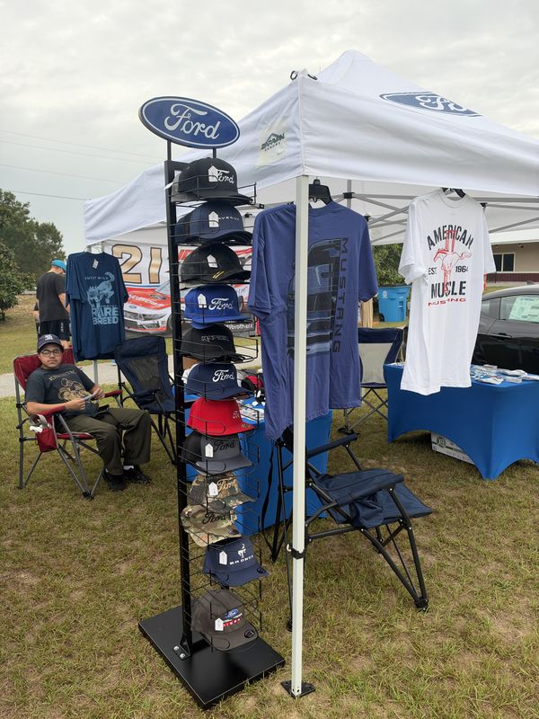 Ford-branded tent with a rack of Ford caps and Ford T-shirts on display at the 46th Annual Mustang & Ford Show in Elgin, SC
