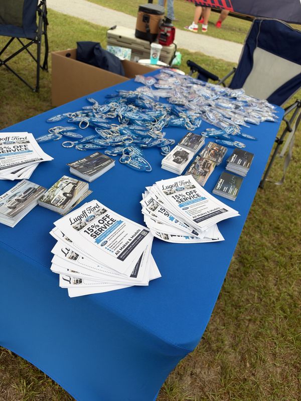Lugoff Ford service coupons and keychains on a blue table at the 46th Annual Mustang & Ford Show in Elgin, SC