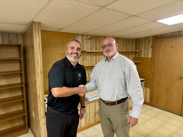 Mark Mason Jr. and Rob Marchant shaking hands in an office after signing the purchase papers