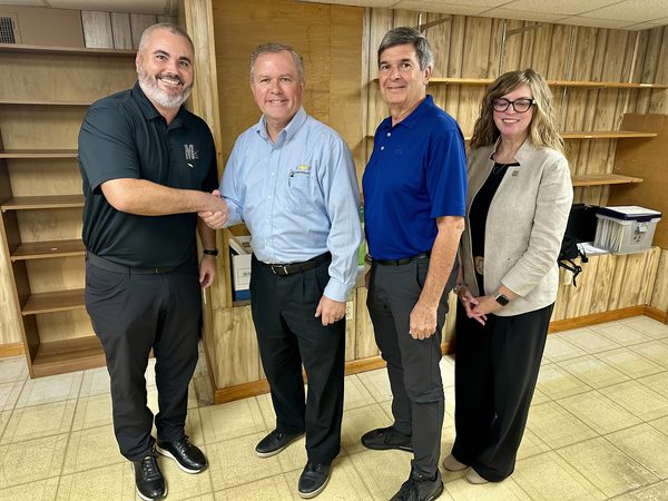 Mark Mason Jr. shaking hands with Ed Bailey of General Motors, with two other people standing beside them